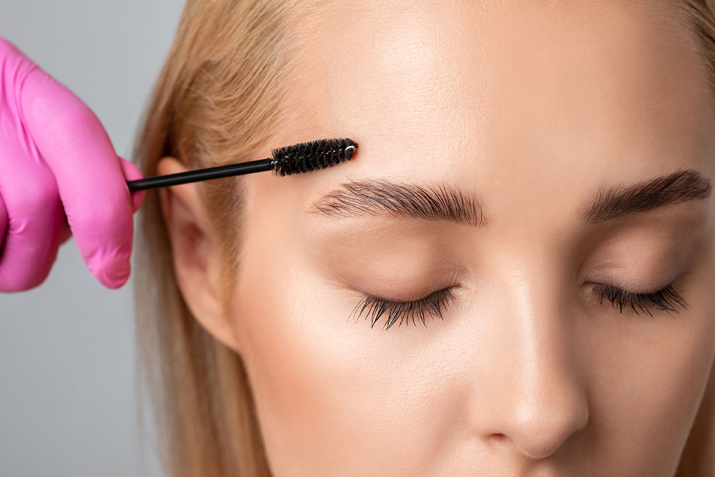 Makeup artist combs and plucks eyebrows after dyeing in a beauty salon.Professional makeup and cosmetology skin care.